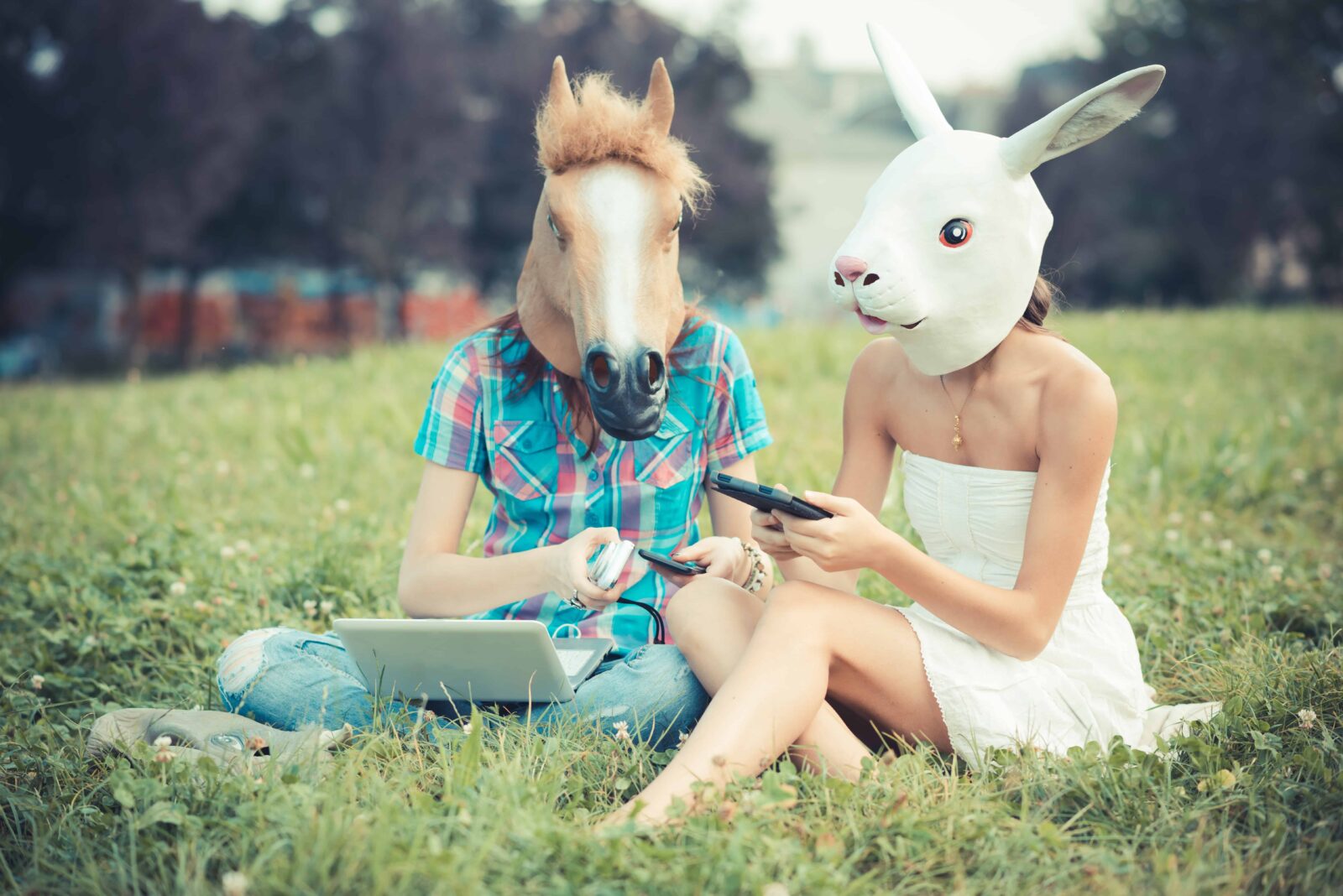 mask horse and rabbit women sisters friends using smartphone and tablet in the park
