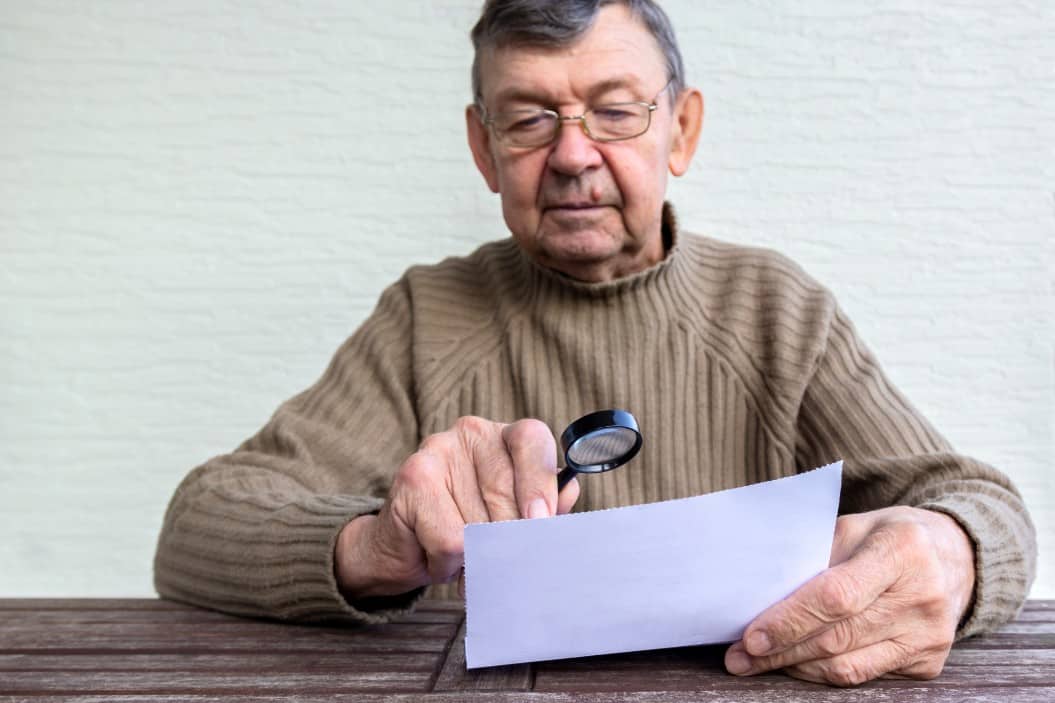 elderly-man-reads-fine-print-on-white-piece-of-paper-using-magnifying-glass-magnifier-helps-old_t20_oR6edA